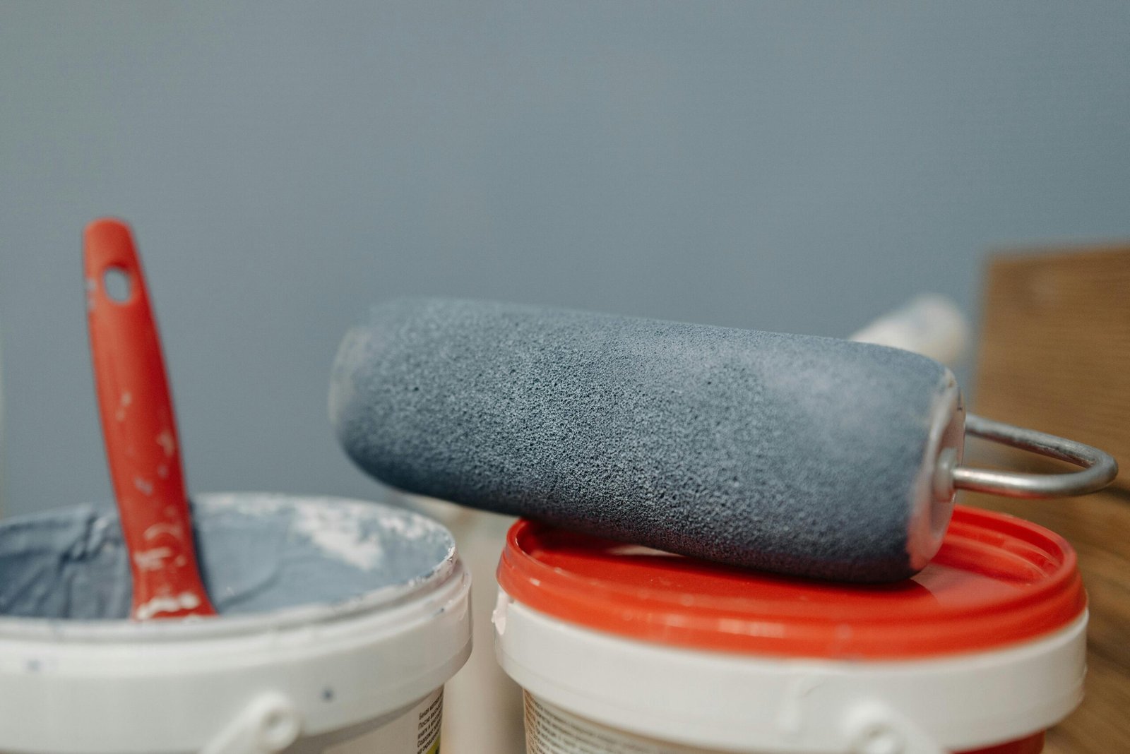 Home A detailed look at a paint roller resting on paint buckets with a blue color scheme.