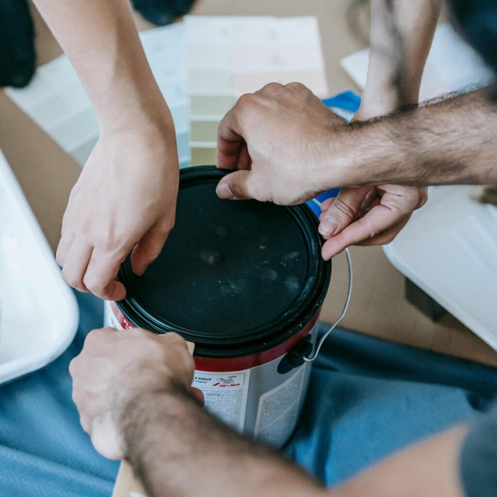 Close-up of a couple opening a paint can, preparing for a home renovation project indoors.